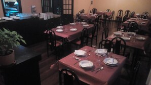 A restaurant with multiple tables set for dining, each with plates, cutlery, and glasses. - Hospedaxe Don Manuel (O Vicedo)