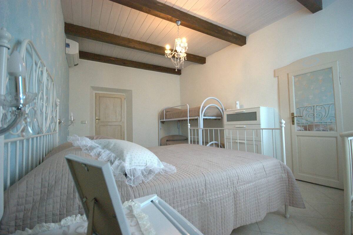 A bedroom with a bed, a chandelier, a wardrobe, and a door.