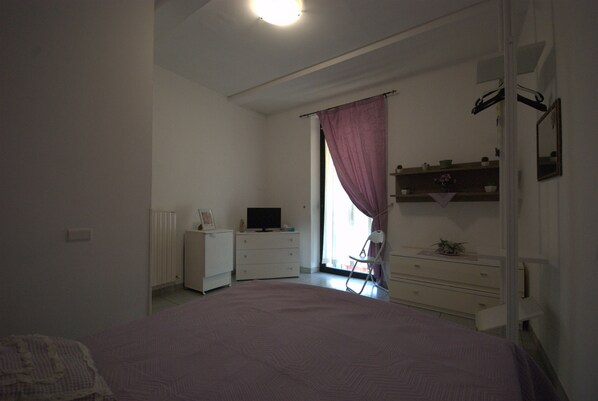 A bedroom with a bed, a dresser, a television, and a window with curtains. - B&B Vittorio Emanuele (San Benedetto del Tronto)
