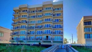 A multi-story hotel with balconies, a wooden walkway, and a clear sky. - Florence I 608 Minium Studio Bedroom Condo by RedAwning (South Padre Island)