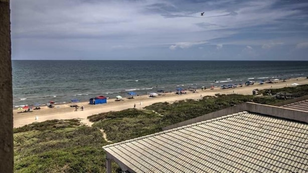 A beach view with tents and umbrellas, a sandy shore, and a cloudy sky. - Florence I 608 Minium Studio Bedroom Condo by RedAwning (South Padre Island)