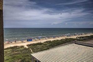 Una spiaggia con tende e ombrelloni, una riva sabbiosa e l'oceano.