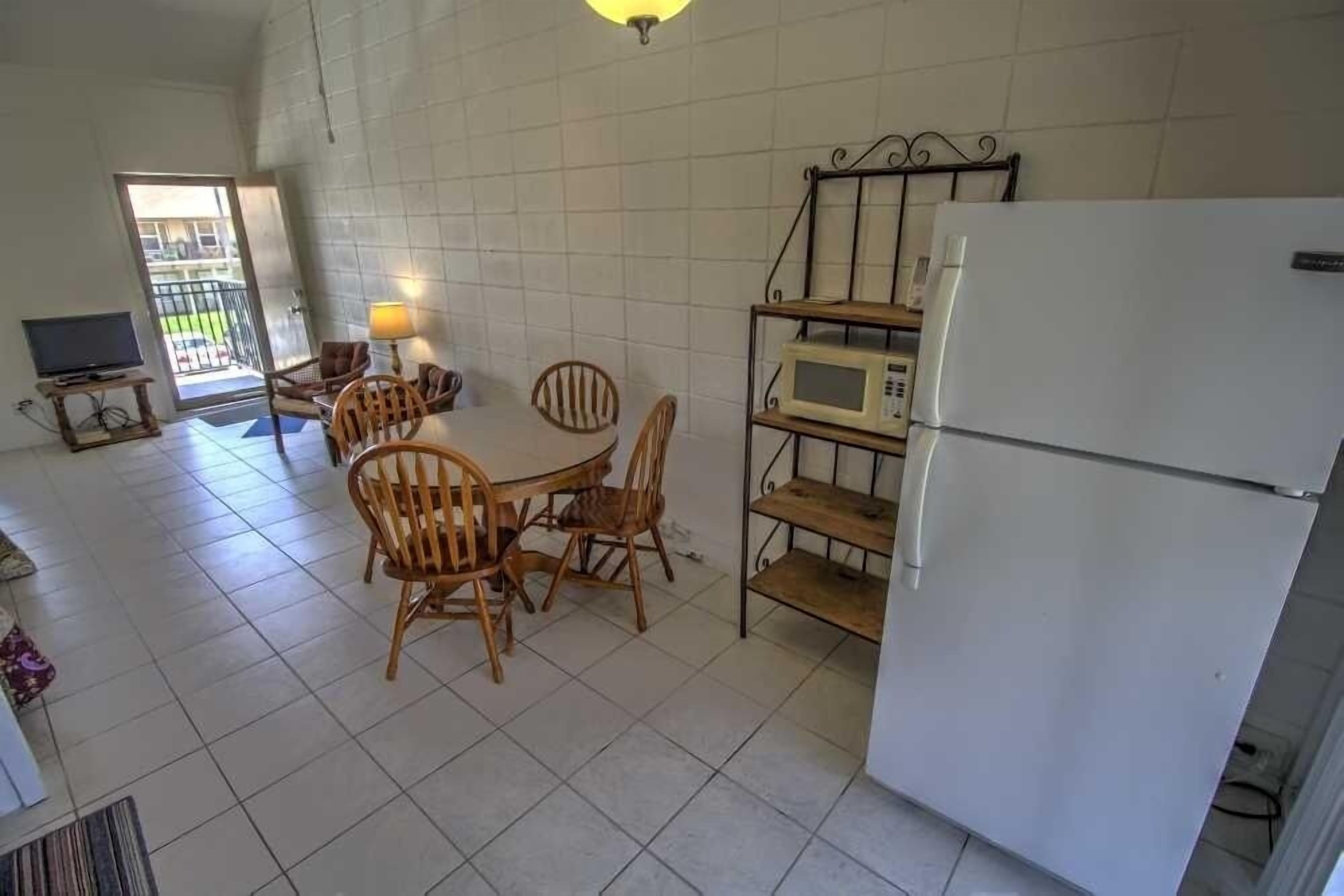Eine Küche mit Esstisch, Stühlen, einer Mikrowelle, einem Kühlschrank und einem Fernseher.