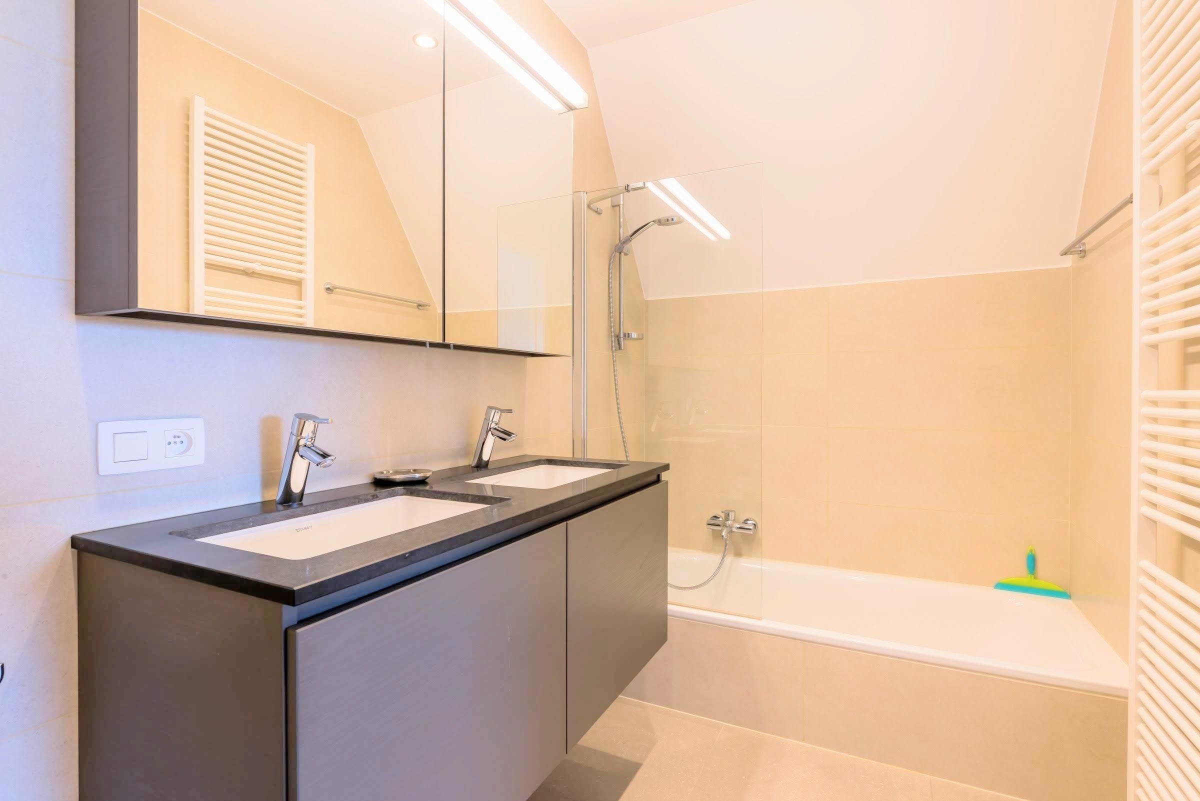 A modern bathroom with two sinks, a shower, and a bathtub.