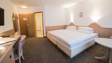 Ein Hotelzimmer mit Bett, Schreibtisch, Stuhl und einem kleinen Tisch.