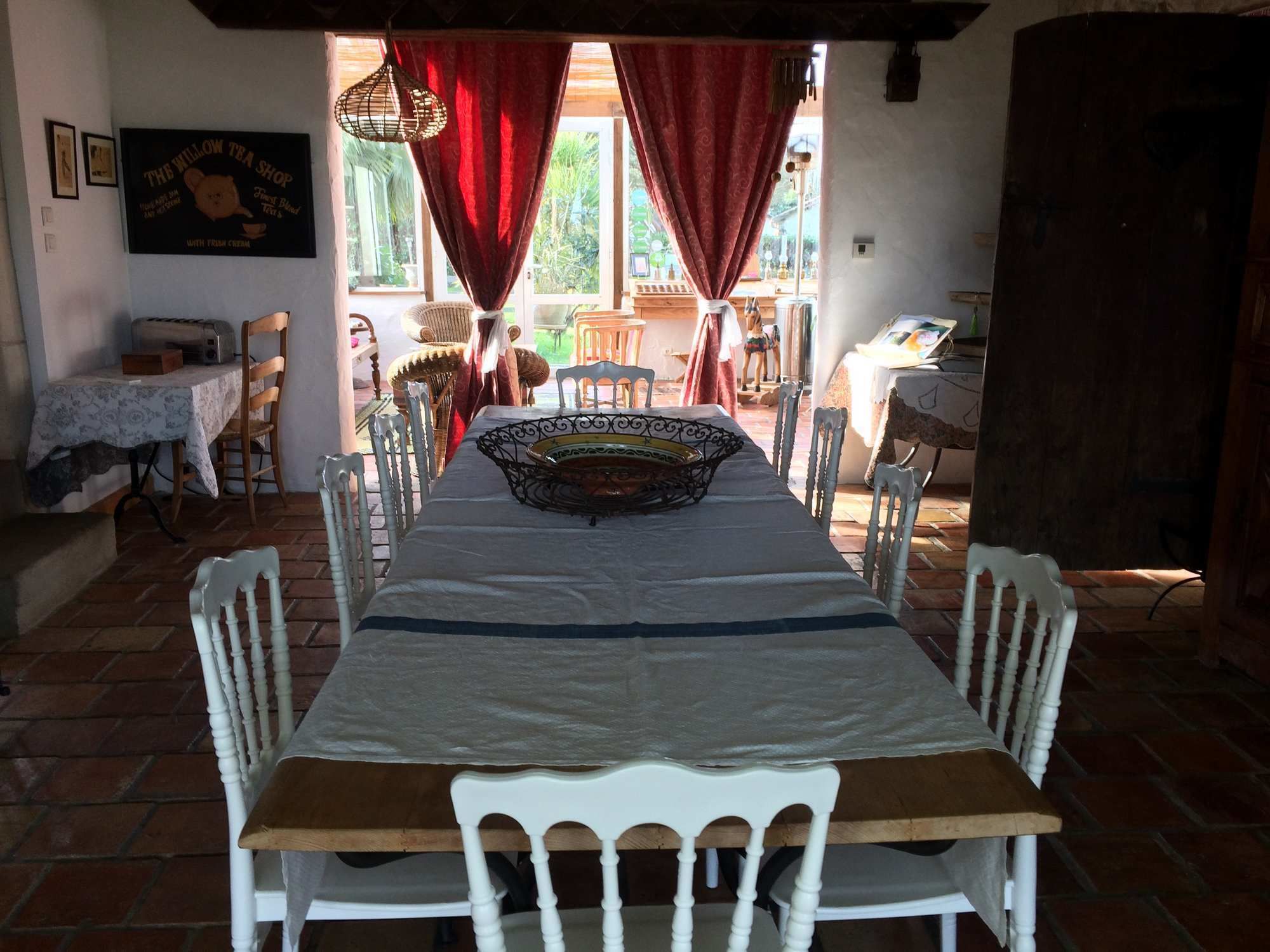 A dining area with a long table, white chairs, and a central decorative bowl.