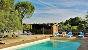 A swimming pool with lounge chairs and a wooden deck. - Maison Basta (Orthevielle)