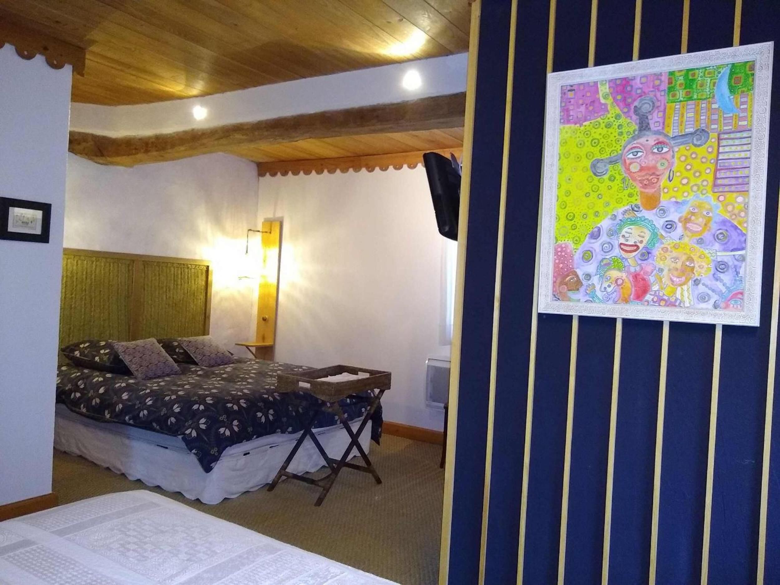 Een slaapkamer met een bed, een staande lamp en een schilderij aan de muur.