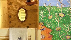 A bathroom with a stone wall, a wooden door, a towel, and a mural of a moon and trees. - Maison Basta (Orthevielle)