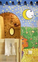 Un baño con pared de piedra, puerta de madera, una toalla y un mural de luna y árboles.