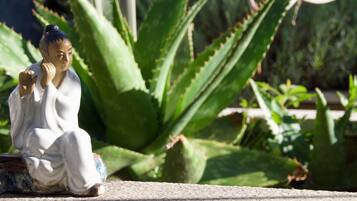 Una statua raffigura una persona in abiti tradizionali seduta su una superficie in pietra.