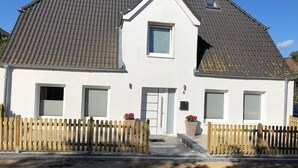 A two-story house with a gabled roof, a front door, and a small window above the door. - Haus Strandoase (Behrendorf)