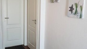 A hallway with a wooden floor, white walls, and two white doors. - Haus Strandoase (Behrendorf)