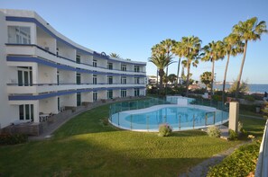 A hotel with a pool, palm trees, and a view of the sea.