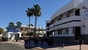 A hotel with a modern design, featuring a curved facade, multiple balconies, and a prominent sign. - Apartamentos Arco Iris (San Bartolomé de Tirajana)
