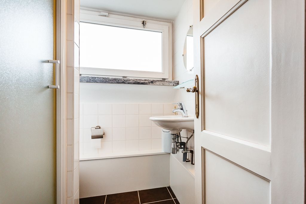 A small bathroom with a window, a sink, and a toilet.