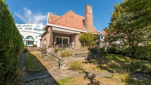 A house with a brick chimney, a stone pathway, and a small garden. - Marsouins (Koksijde)