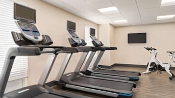 Une salle de sport équipée de plusieurs tapis de course, de vélos d’appartement et d’appareils de cardio-entraînement.