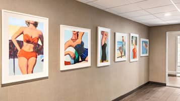 A hallway with framed artwork on the walls and a wooden floor.