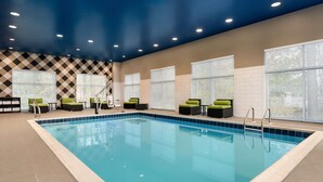 An indoor swimming pool with clear blue water, surrounded by lounge chairs and a checkered wall pattern. - Hampton Inn & Suites Ocean City West (Ocean City)