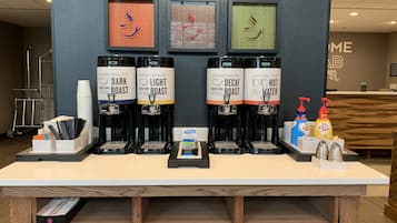 A coffee station with three coffee dispensers labeled 'Dark Roast,' 'Light Roast,' and 'Decaf Roast.' There are also condiments and napkins on the counter.