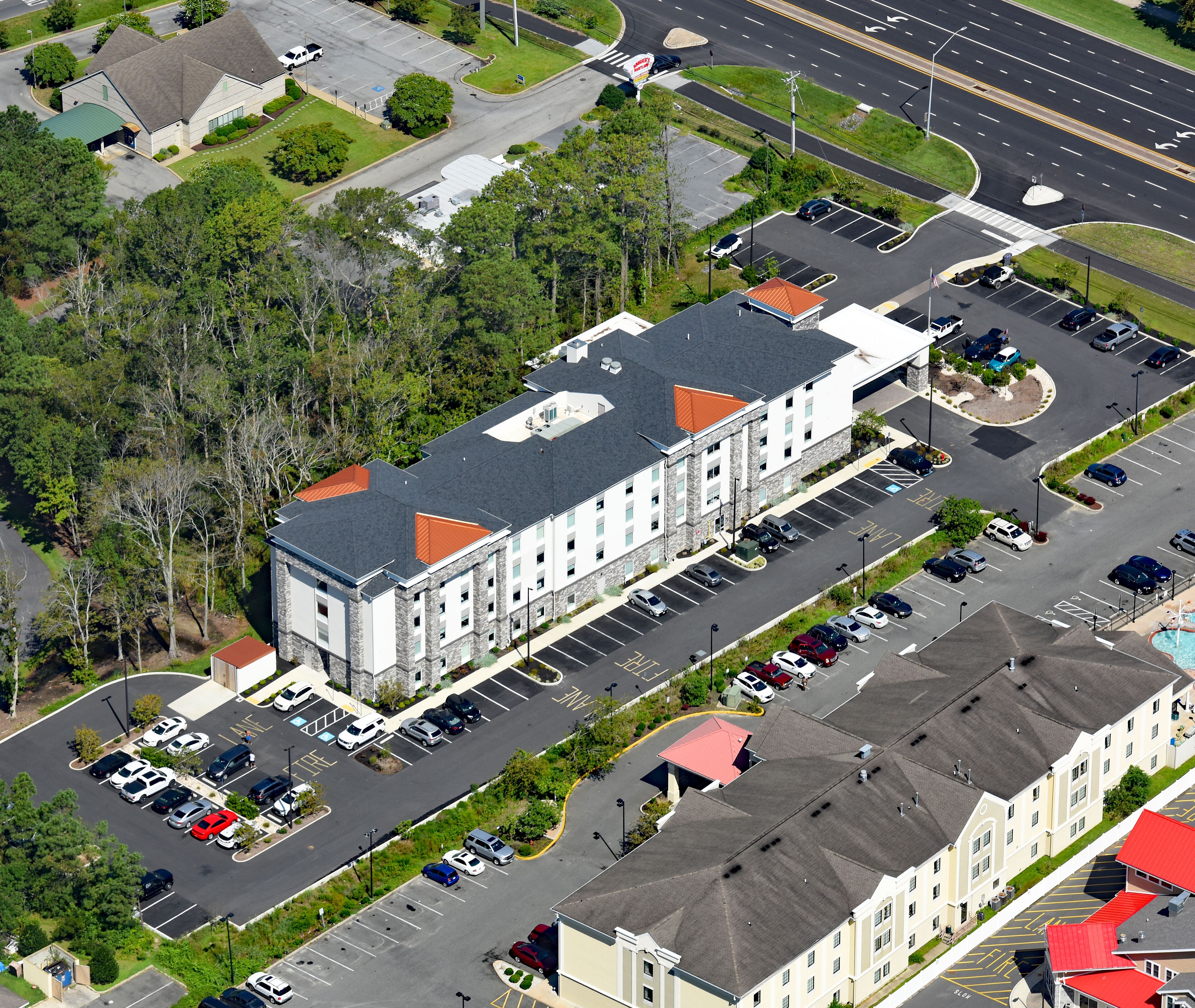 An aerial view of a multi-story building with a parking lot in front.