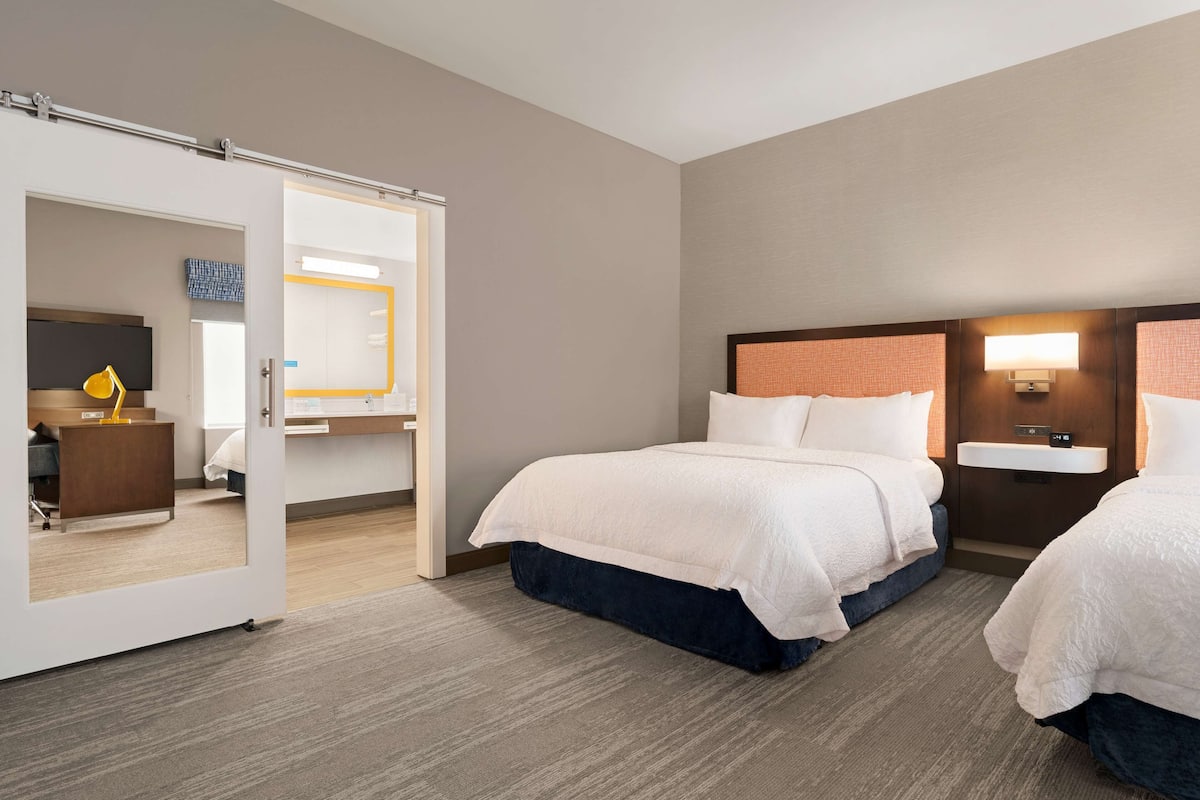 A hotel room with a bed, bedside table, and a mirror.