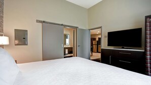 A hotel room with a large bed, a flat-screen TV, a wardrobe, and a bathroom visible through an open door. - Home2 Suites by Hilton Amherst Buffalo (Buffalo)