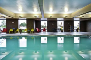 A swimming pool with yellow and red chairs, a table, and a ladder. - Home2 Suites by Hilton Amherst Buffalo (Buffalo)