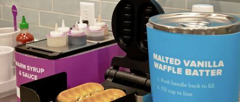 Máquina de waffles com instruções e um recipiente rotulado como 'Massa para Waffles Maltada de Baunilha'.
