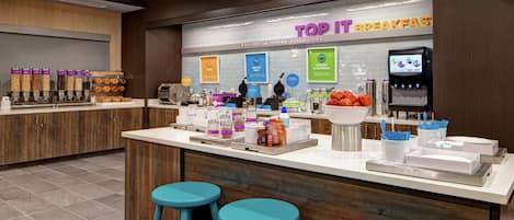 Een ontbijtbuffet met een bord waarop 'TOP IT BREAKFAST' staat en diverse etenswaren.