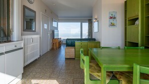 A modern kitchen with a dining area, a large window, and a view of the sea. - Magellan 701 (Koksijde)