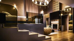 A modern hotel room with a bed, a fireplace, a large mirror, and a staircase. - Penthouse Suite Rome (Rome)