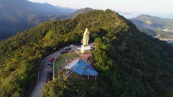 Uma estátua numa colina, com uma estrada e uma área coberta nas proximidades.