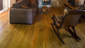 A cozy living room with a stone wall, a fireplace, a sofa, a rocking chair, and a television. - Casa de Santa Cristina (Marco de Canaveses)