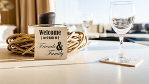 Ein Willkommensschild mit dem Aufdruck 'Friends & Family', ein Glas Wasser und ein Korbwägelchen auf einem Tisch.