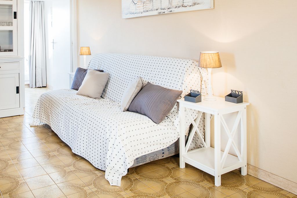 Una camera da letto con un letto, due cuscini, un comodino con una lampada e una piccola mensola con oggetti decorativi.