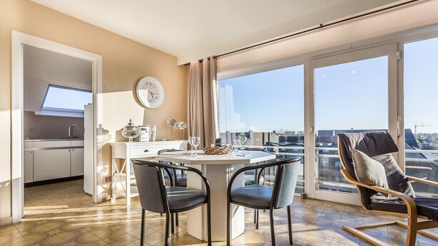 Ein modernes Wohnzimmer mit Essbereich, großen Fenstern und Blick auf die Stadt.