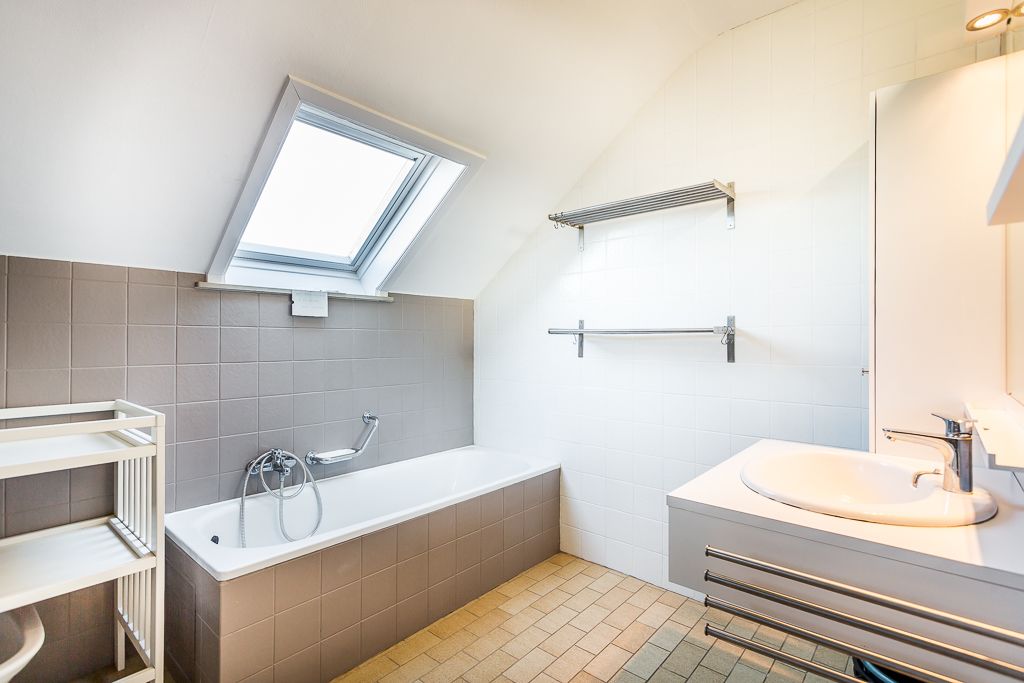 Un baño moderno con tragaluz, una bañera, un lavamanos y un perchero para toallas.