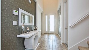 Een moderne badkamer met een patroon op de muur, een grote spiegel, een toilet en een wastafel met decoratieve objecten.
