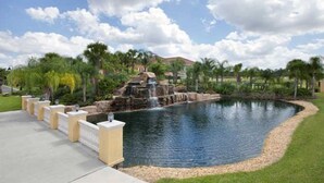 A landscaped pond with a waterfall, surrounded by palm trees and a paved walkway. - Paradise Palms 4 Bed Townhome w Splashpool - 3281PP (Kissimmee)