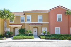 A row of townhouses with a consistent architectural style, featuring a central entrance with a door and a small porch area. - 2651en (Kissimmee)