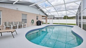 Une piscine extérieure couverte, dotée de chaises longues et d’un espace barbecue.