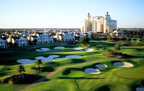 En golfbana med bunkrar och ett hotell i bakgrunden.