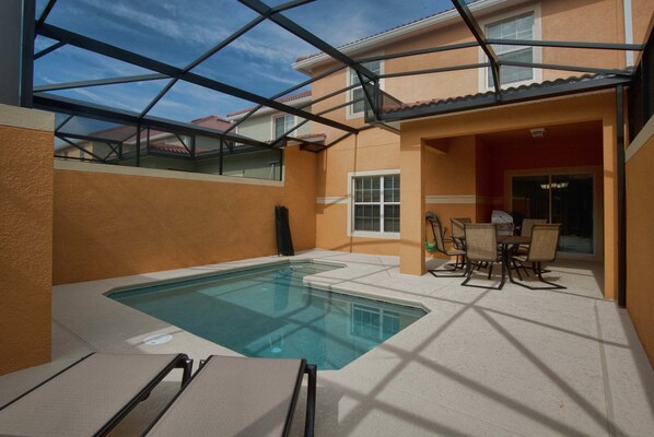 A swimming pool with a glass ceiling, surrounded by a patio area with outdoor furniture.