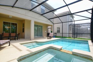 Ein Schwimmbad mit Glasveranda, eine Terrassenfläche mit Tisch und Stühlen sowie ein überdachter Sitzbereich.
