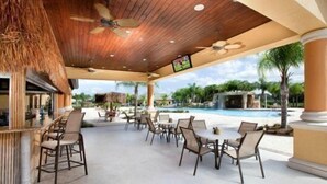 Un espace extérieur aménagé avec des tables et des chaises, une piscine et un ventilateur de plafond.