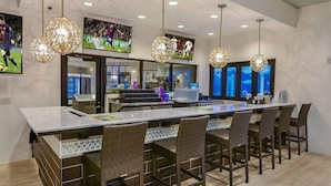 Eine moderne Küche mit einer großen Kochinsel, einer Bar und Pendelleuchten.