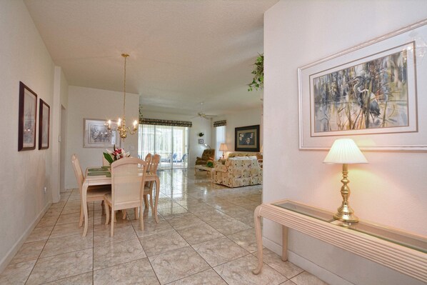 A spacious living area with a dining table, chairs, a sofa, and a painting on the wall. - 4100es (Davenport)