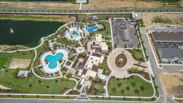 An aerial view of a resort with a large swimming pool, a water park, and a parking lot. - Solara 9 Bedroom House w Pool - 8100SA (Kissimmee)